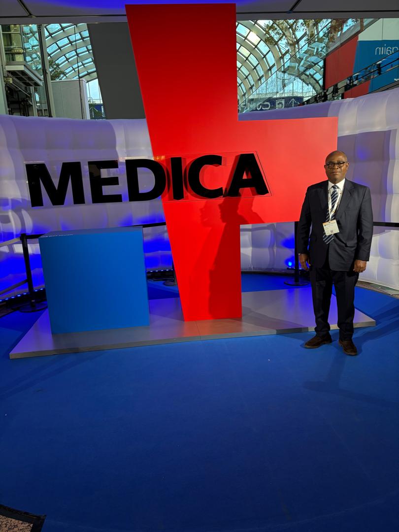 Membre de l'équipe LOGISTIQUE MEDICA-CI devant l'emblème du salon MEDICA